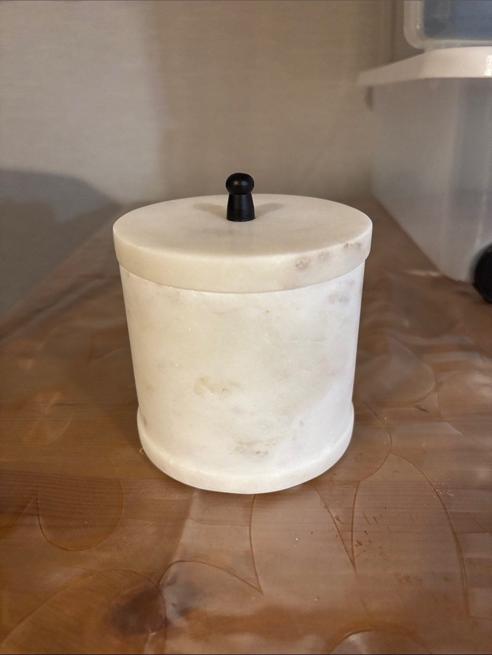 white marble canister with a black knob on its lid.